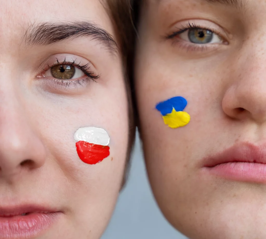 dwie stykające się poważne twarze pomalowane w barwach Ukrainy i Polski