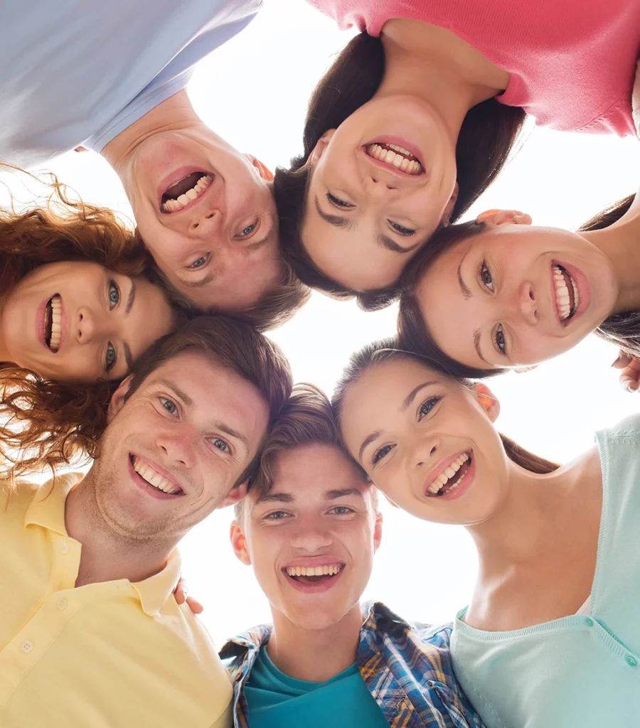 krąg uśmiechniętych i poważniejszych twarzy młodych dziewczyn i chłopców