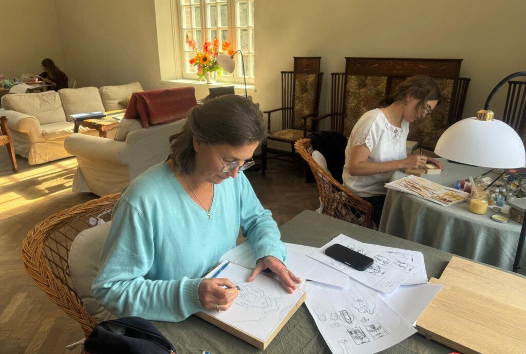 Dwie malarki przy pracy w oświetlonym słońcem wnętrzu