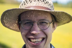 Roześmiana twarz chłopaka w okularach i słomkowym kapeluszu