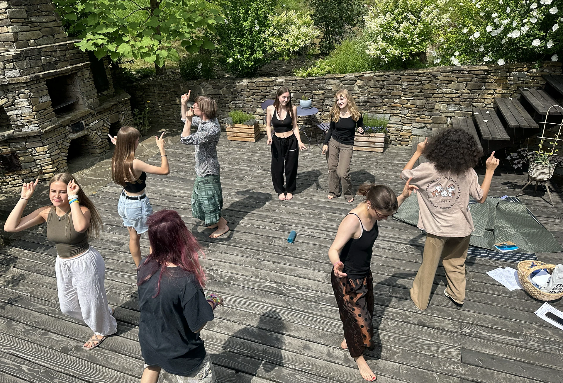 Młodzi ludzie tańczą na parkiecie z desek w słońcu.